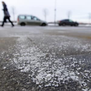 De-icing chemicals on the road. Pavement is sprinkled with technical salt or salt mixtures based on it, soft focus, blurred background. Reagent - technical salt will make the road safe.